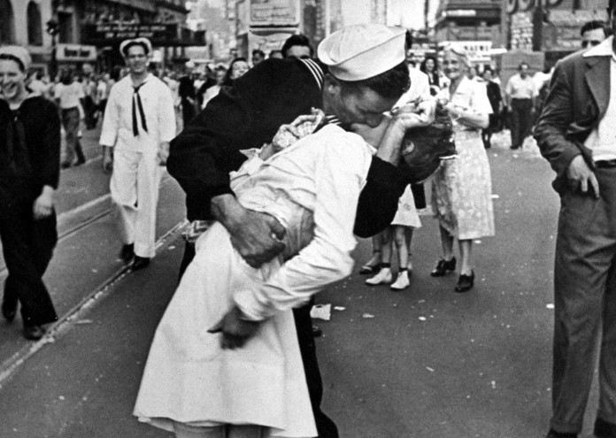 Войник в униформа прегръща жена през кръста, нейният гръб е