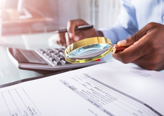  Businessman Holding Magnifying Glass Over Invoice 